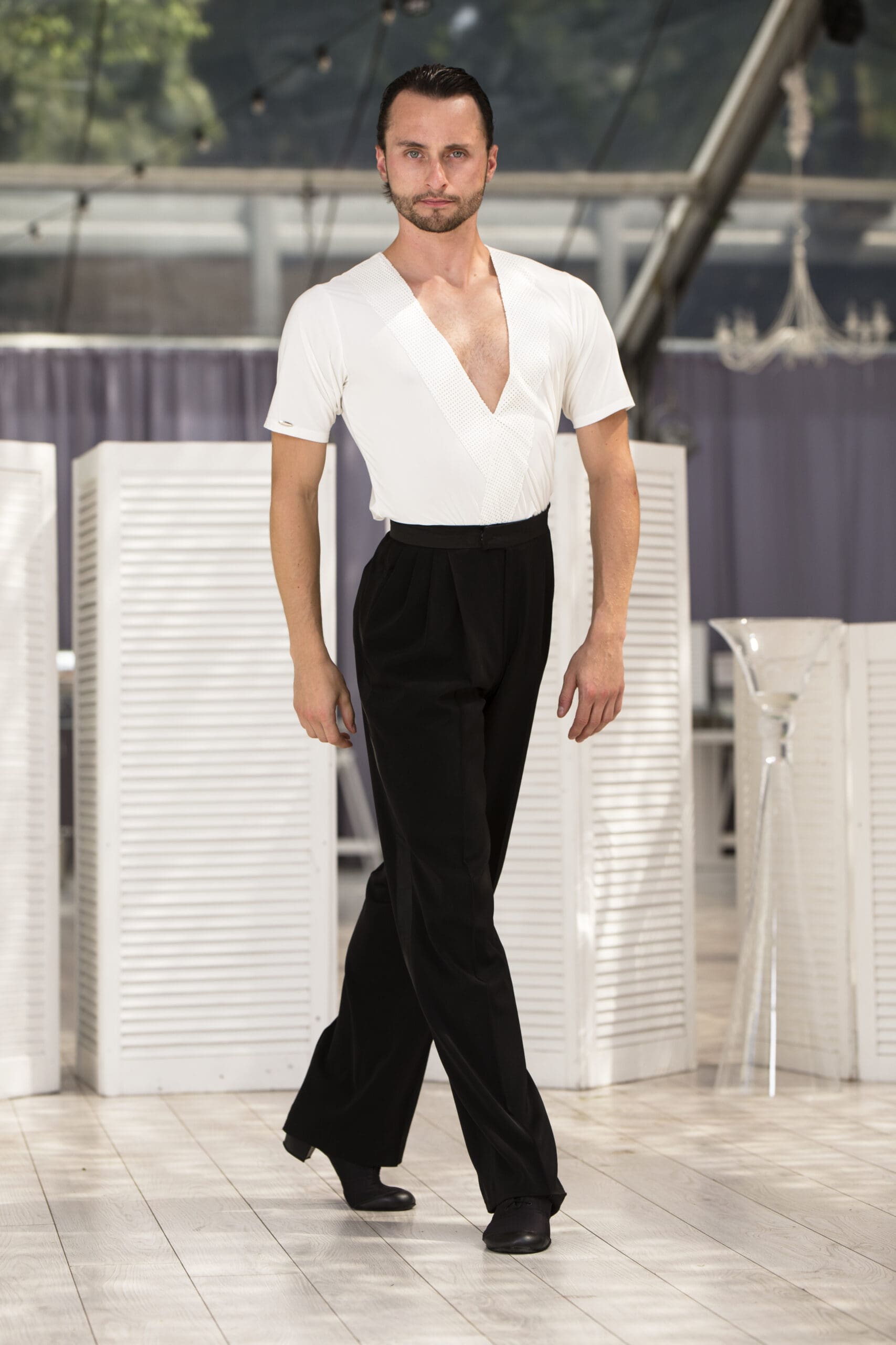 Man performing in elegant dancewear featuring a white top and black trousers.