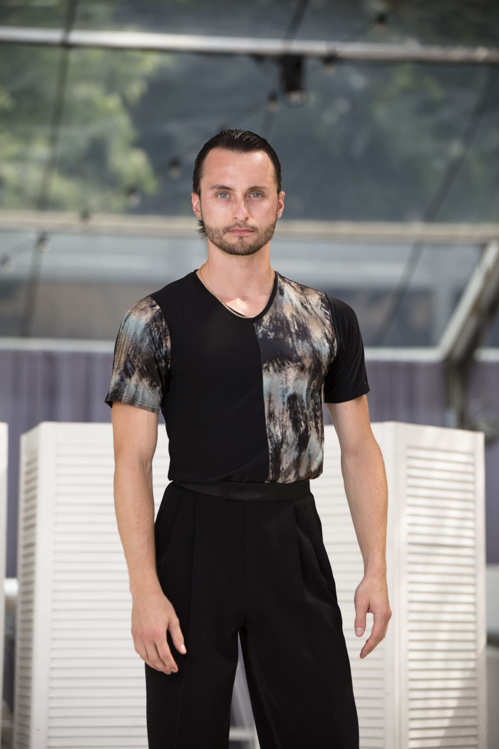 Male dancer wearing a stylish black and patterned top with black trousers.