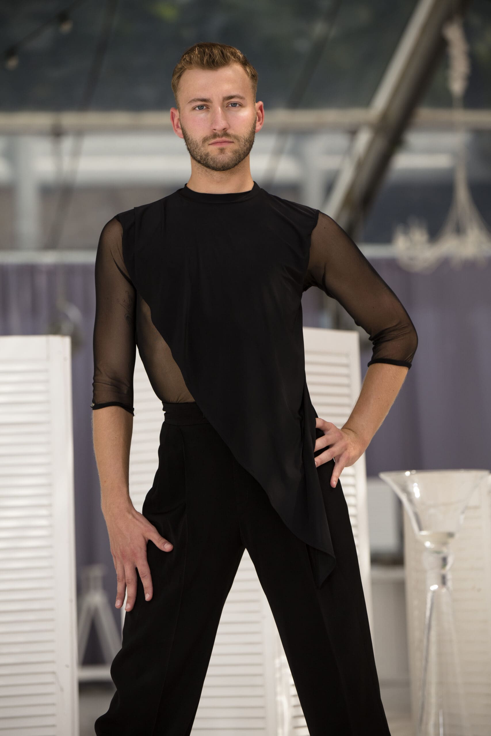 Male model showcasing an elegant black dance outfit with sheer details.